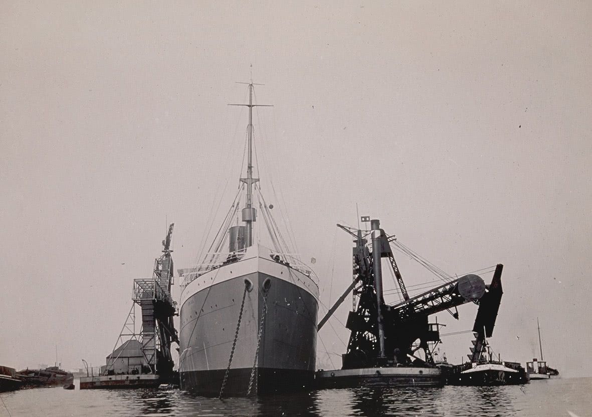 A large ship is loaded by an SHV elevator-transporter, c. 1910.